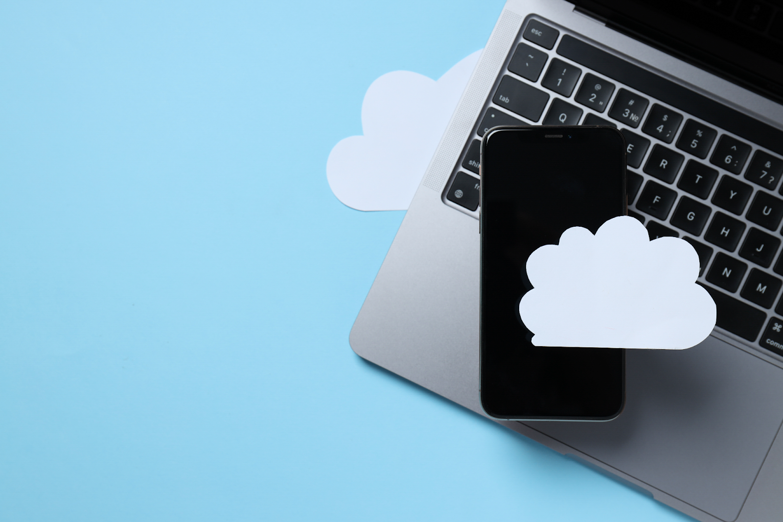 iPhone och MacBook med moln iPhone och MacBook med moln som symboliserar iCloud-synkronisering