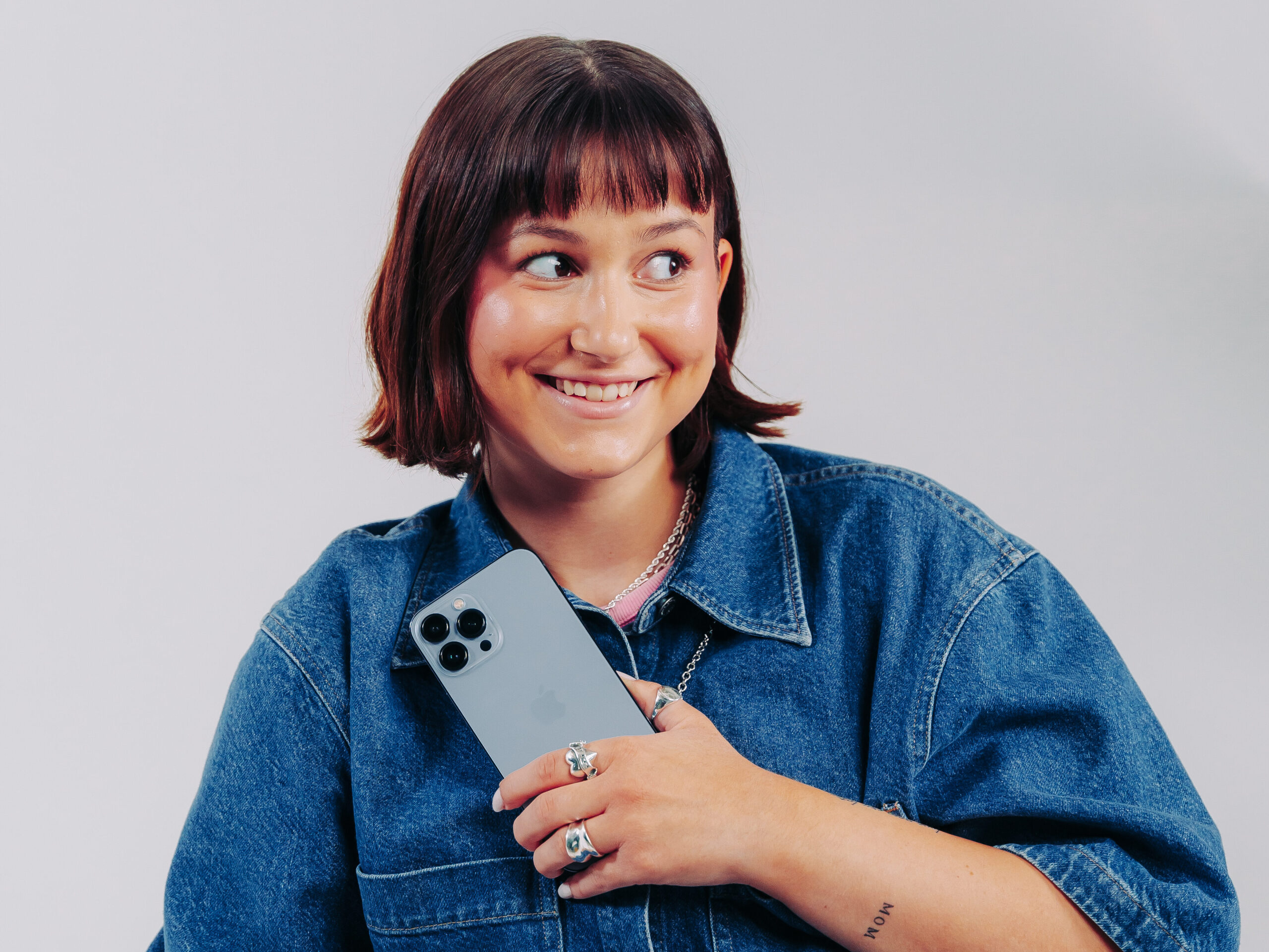 Tjej håller iPhone vid bröstkorgen Tjej som håller sin iPhone nära bröstkorgen som symboliserar att skydda sina personuppgifter