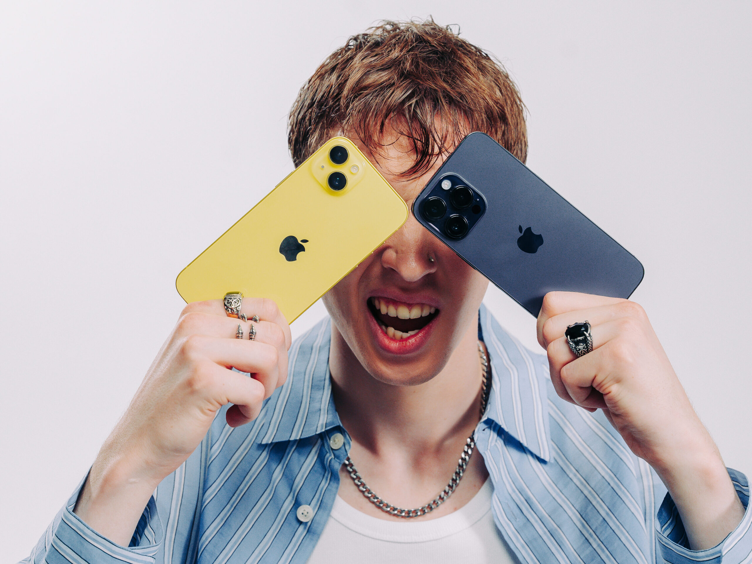 Kille håller två iPhones för ögonen Kille som håller en iPhone för vardera öga