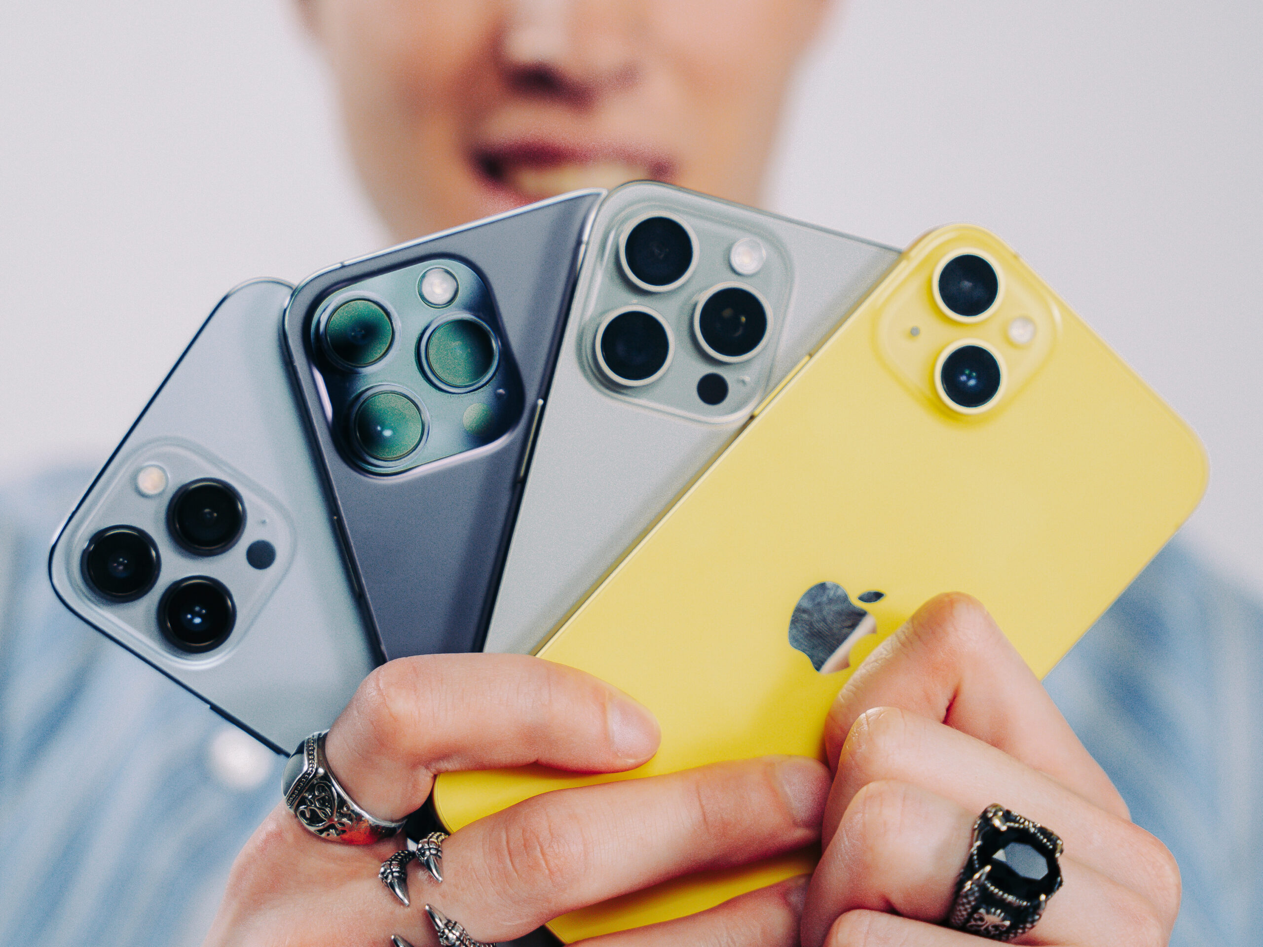 Fyra olika iPhone-modeller Kille håller upp fyra olika iPhone-modeller