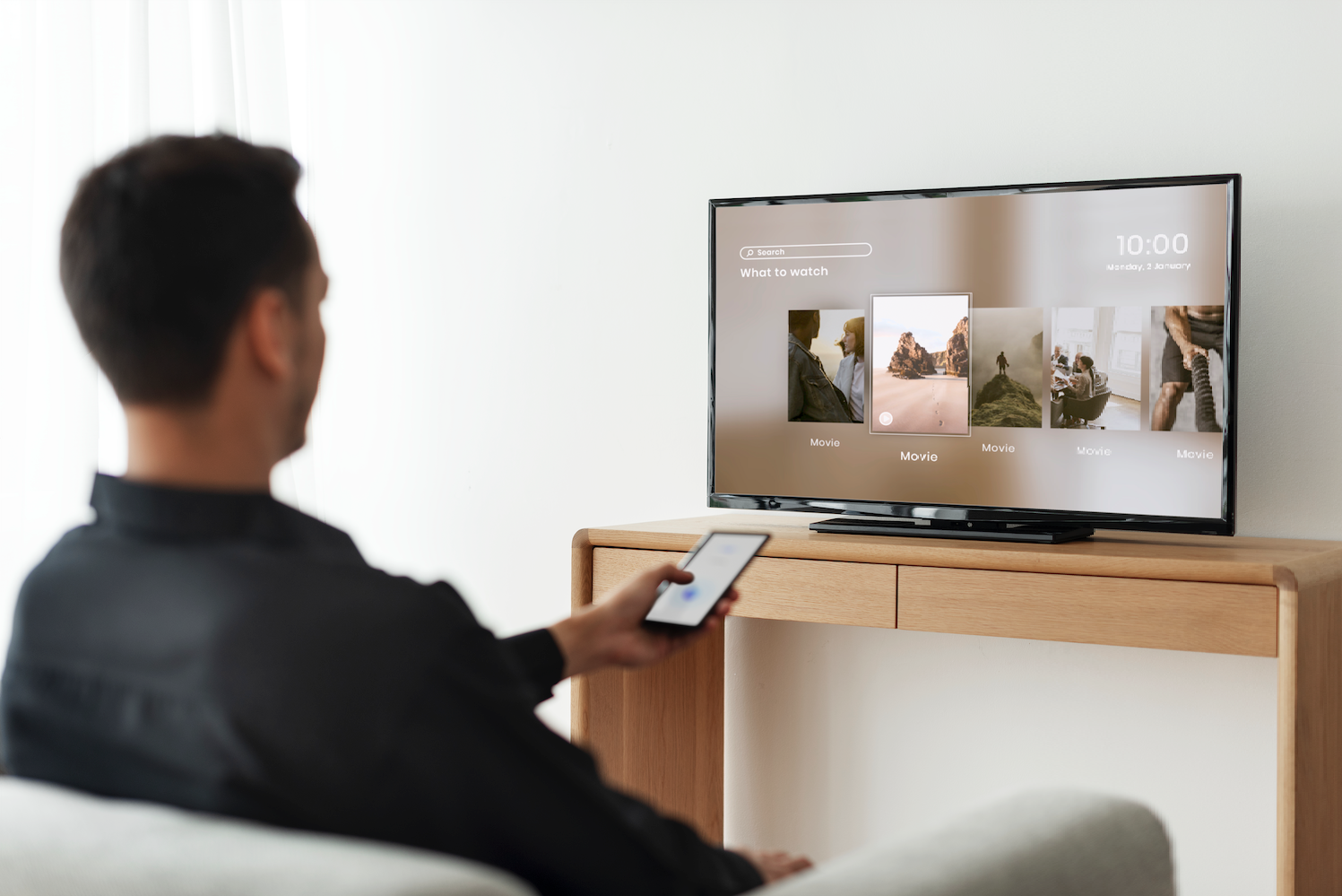 man controlling smart tv using iPhone