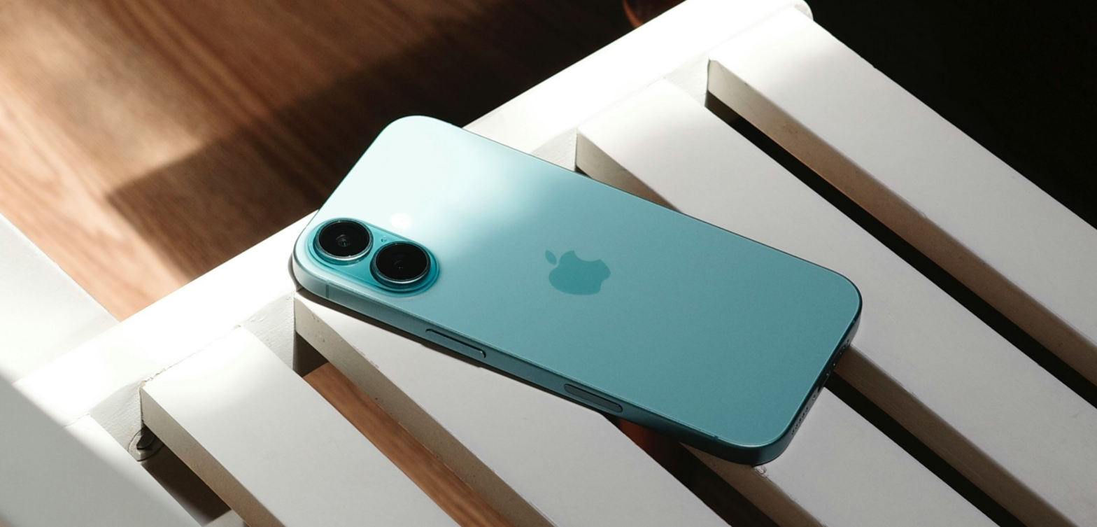 iPhone 16 Plus in teal on a bench